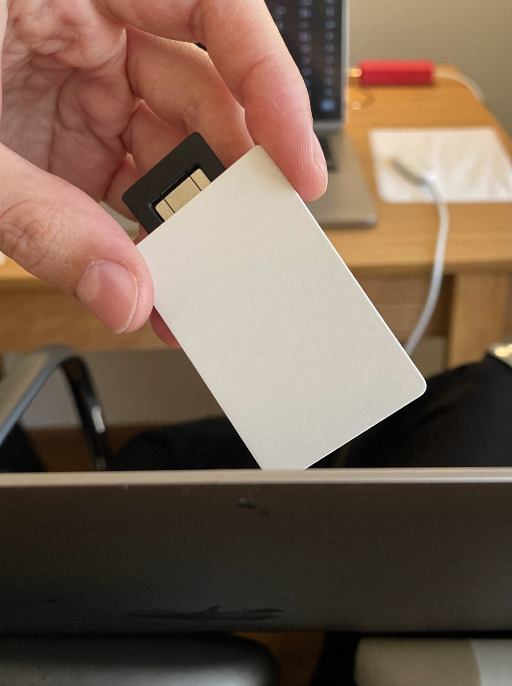 Mão inserindo um cartão inteligente em branco numa leitora conectada a um notebook